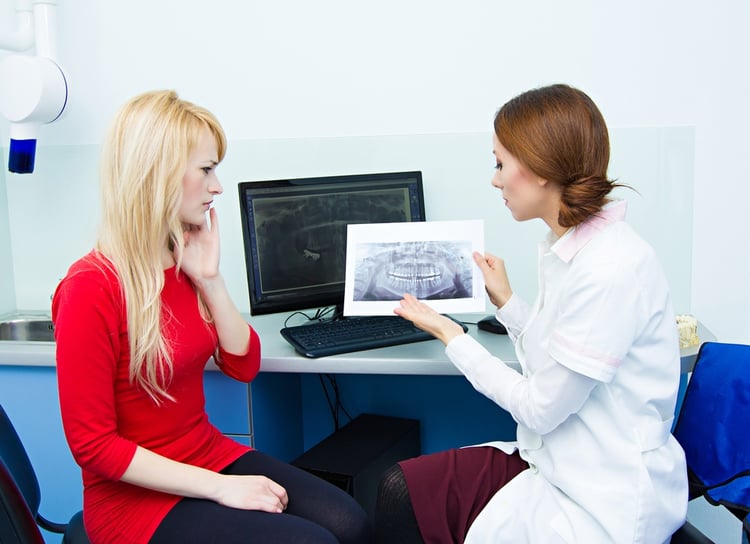 Closeup portrait female health care professional, dentist, holding showing panoramic dental X-ray, consulting woman patient having toothache..jpeg