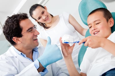 Dentist showing a boy how to brush his teeth properly.jpeg
