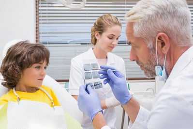 Pediatric dentist showing little boy his mouth xray at the dental clinic.jpeg